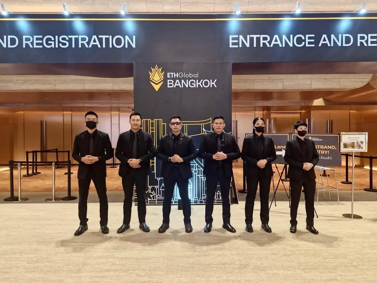 Males and females bodyguards in black suits standing in line in front of Bangkok entrance and registration