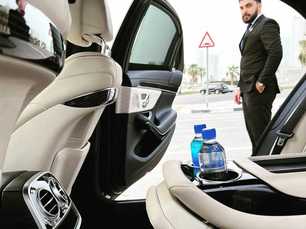 chauffeur opening rear door of premium sedan for private client