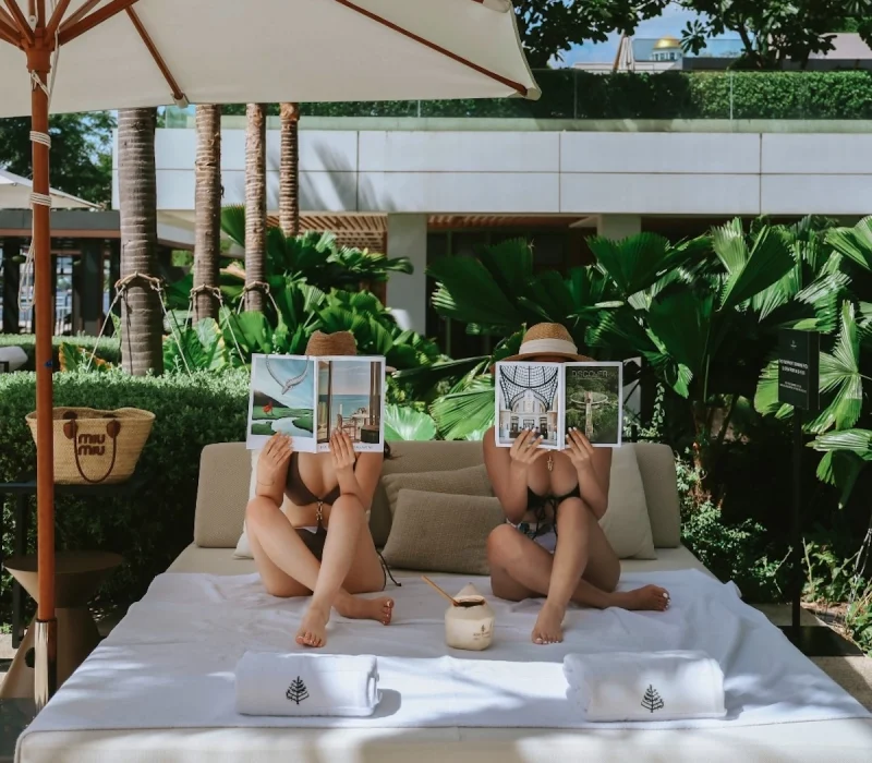 girls in bikini holding magazines at the Four Seasons Bangkok's pool