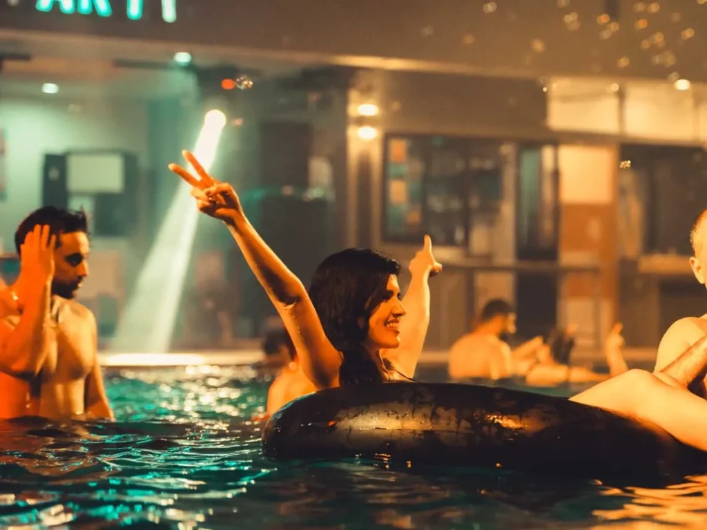guests enjoying a private pool party at night in bangkok with music and floating inflatables