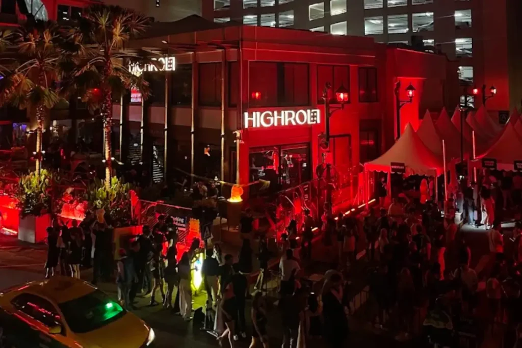 Crowd outside High Roller nightlife venue in Bangkok illuminated by red lights at night