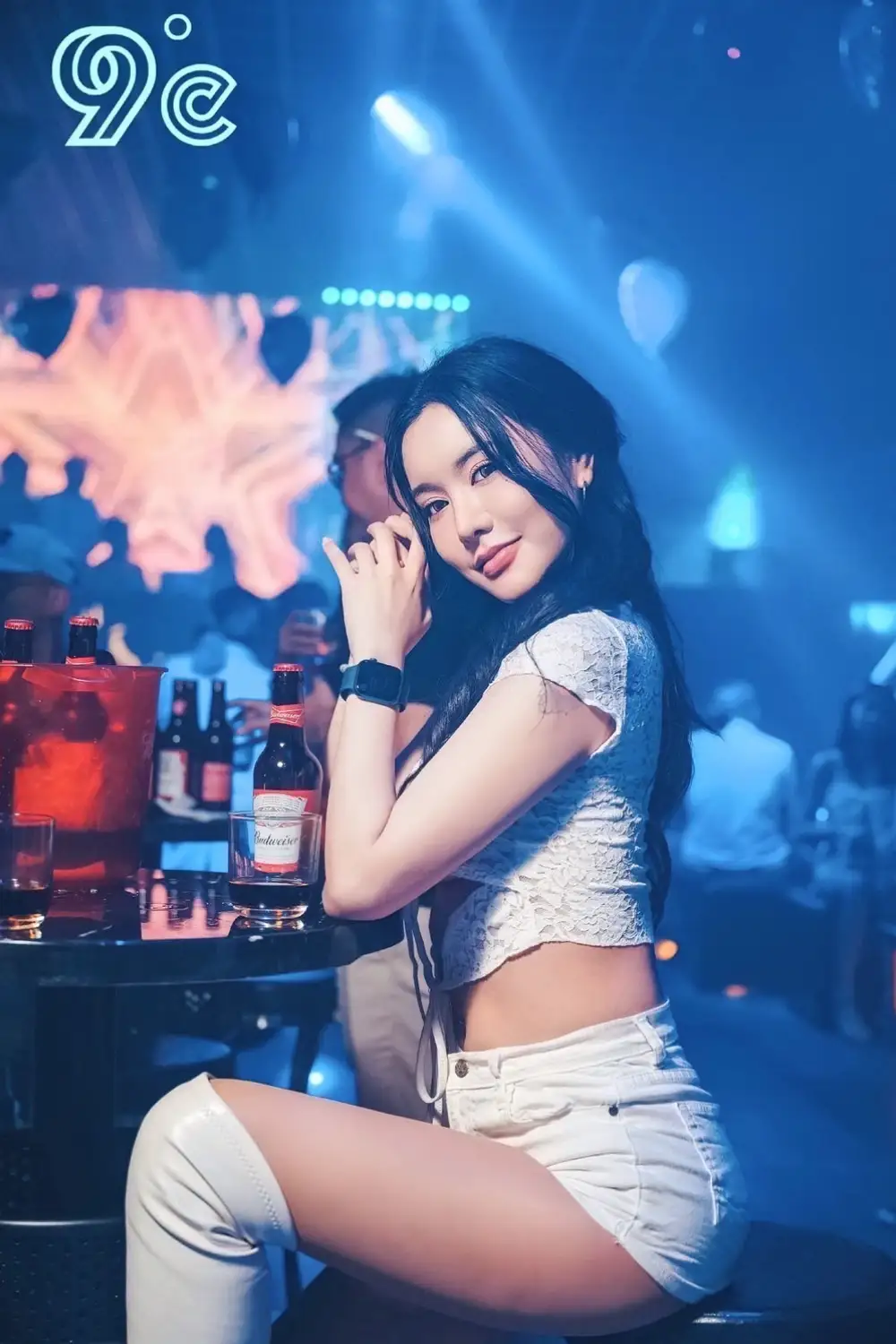 promotion model in white leather boots in a nightclub with a beer